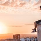 A young man sitting on a rooftop in Ufa, Russia, watching a vibrant sunset.